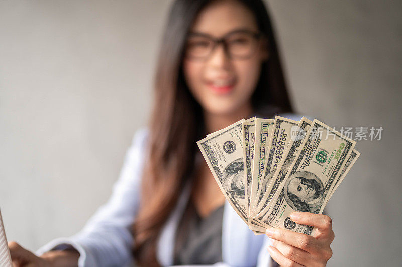 Dollar in a businesswoman's hand. An Asia woman is working from home or office and glad to get dollar money from work and from a supplementary career or Part-time self-employment.